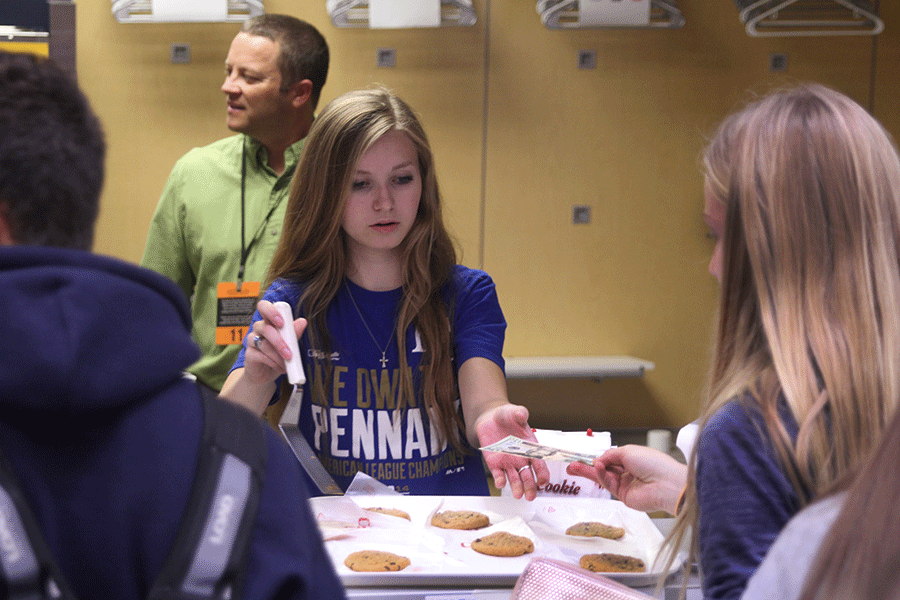 Senior Megan Feuerborn serves a cookie to freshman Lexie Ballard during the Catty Shacks grand opening in seminar on Friday, Oct. 23. 