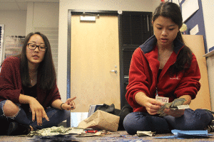 After school on Tuesday, Oct. 6, junior Sue Kim and senior Camille Gatapia count money, which students raised for the Make-A-Wish Foundation by selling paper stars.