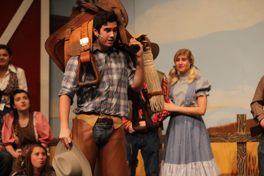 Sophomore Simon Stewart enters the auction holding a saddle over his shoulder.