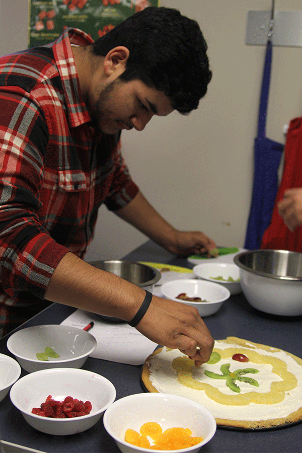 On Oct. 27, Senior Greg Guerrero places grapes on his teams fruit pizza in Nutrition and Wellness.