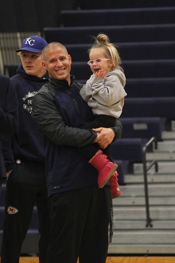 Head coach Joel Applebee holds his daughter during pep rally.