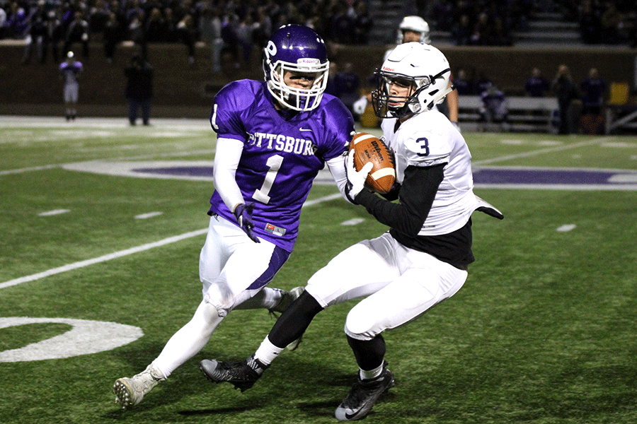 Gripping the ball, senior cornerback Sebastian Peterson dodges the other player.