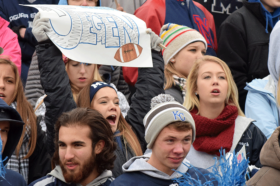 Junior Paige Lewis holds up a sign and cheers on the Jaguar football team during the game. 