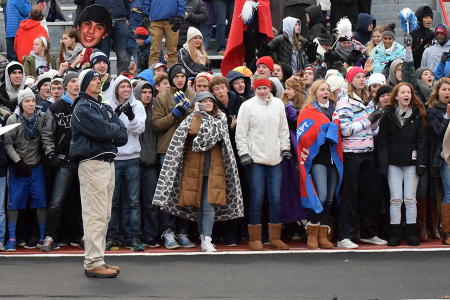 Athletic director Jerald VanRheen holds back the student section from storming the field until after the presentation of the state championship trophy. 