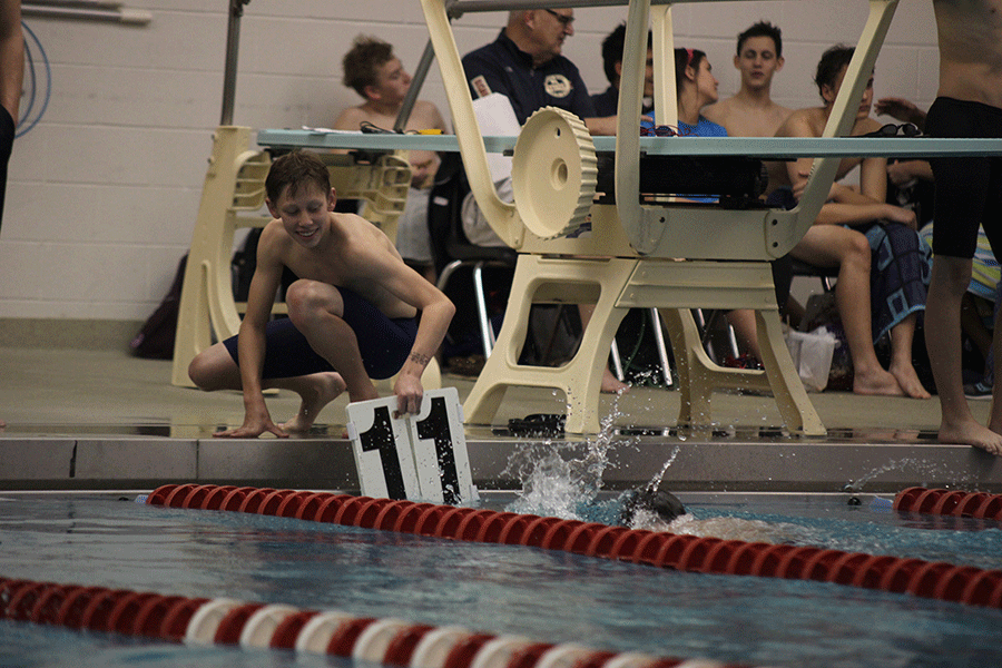 While sophomore Noah Kemper swims, freshman Chris Sprenger signals to him how many laps he has completed.