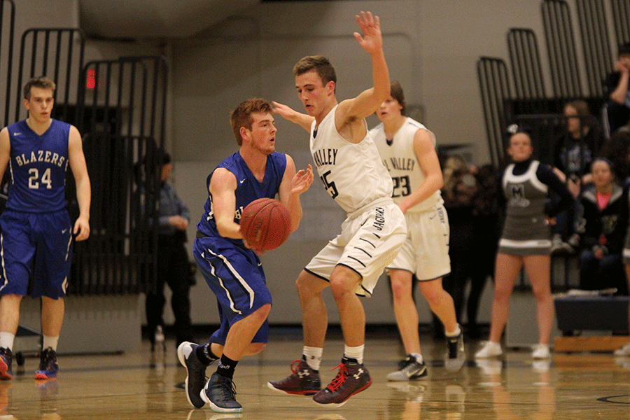 Blocking his opponent during the boys basketball game on Tuesday, Dec. 8, senior Jaison Widmer throws his hands up and shuffles across the court to block a pass.