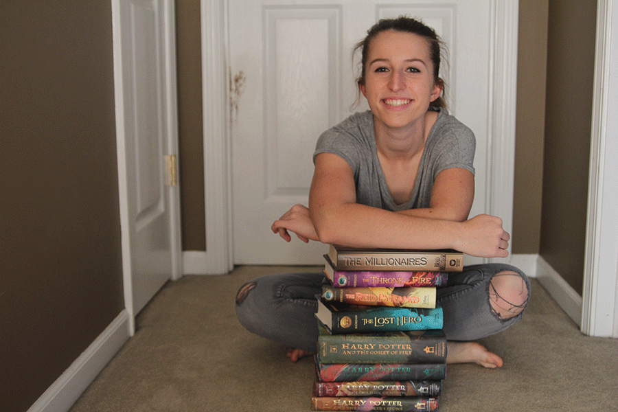 An+avid+reader%2C+sophomore+Madeline+Myrick+sits+with+a+small+portion+of+the+books+she+has+read.+%E2%80%9C%5BI+enjoy+reading%5D+because+it%E2%80%99s+fun%2C+Myrick+said.+You+can+go+on+an+adventure+and+not+move+anywhere.