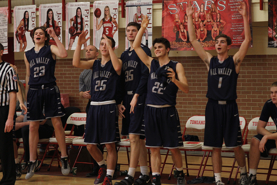 After a three pointer by a teammate, the bench jumps up in celebration,