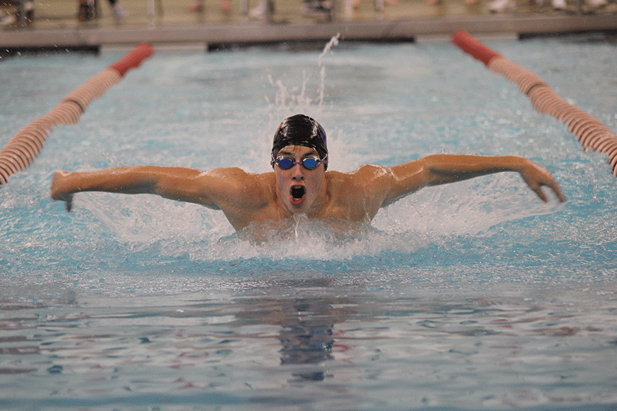 Pulling himself up and out of the water, junior Garrison Fangman inhales as he swims the 100 yard butterfly at Blue Valley West on Thursday, Jan. 28.
