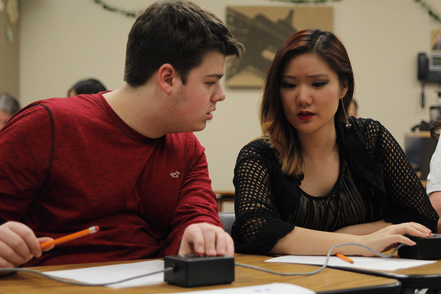 With his hand ready to buzz in, senior Jack Booth discusses the answer to a question with senior Karla Kim at the Quiz Bowl meet on Tuesday, Jan. 26 at St. James Academy.