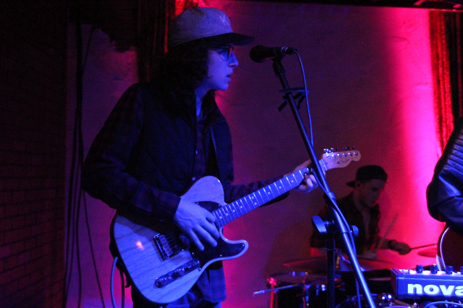 Fisher looks toward the band as he plays guitar.