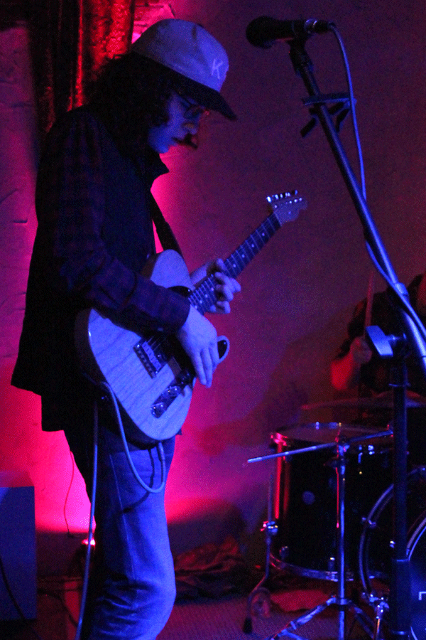 Ingram looks downward while playing guitar.