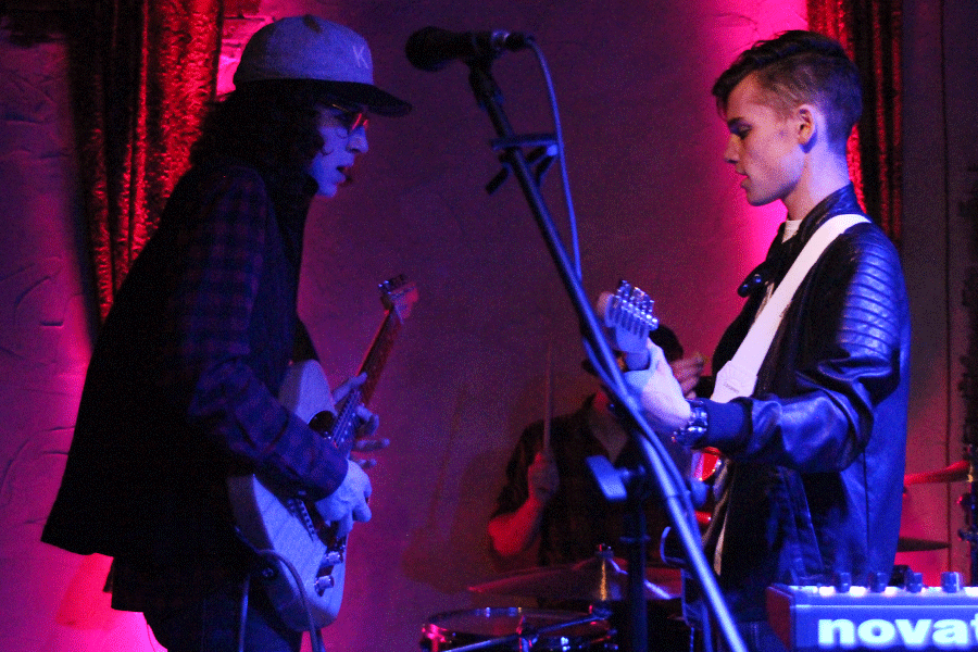 Fisher and Ingram face each other as they play guitar.