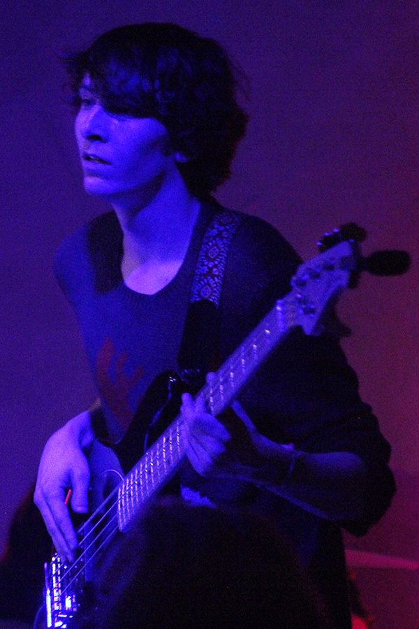 O'Halloran looks toward the audience as he plays bass guitar.