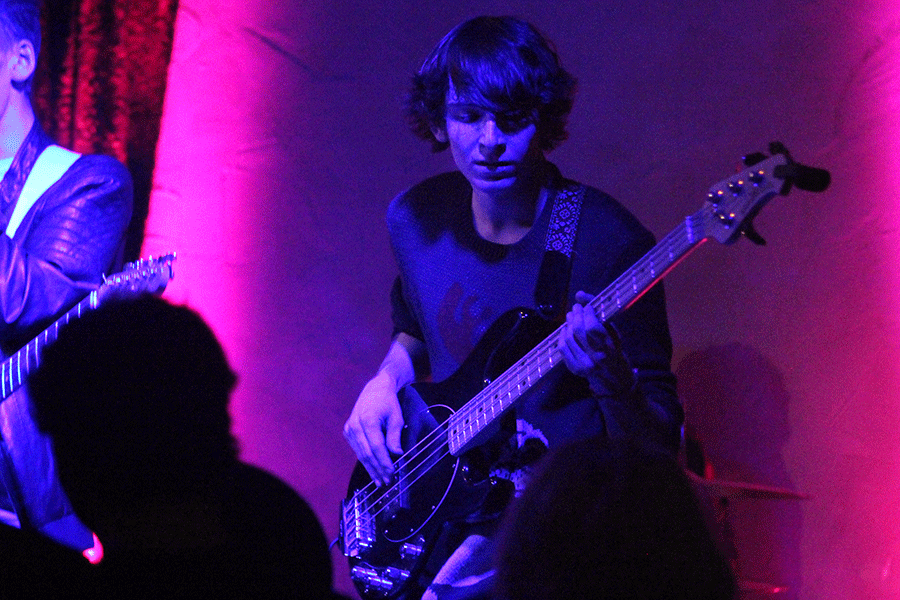 O'Halloran plays bass guitar while looking down.