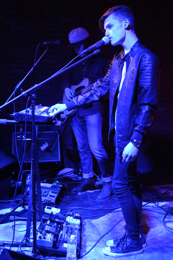 Ingram plays a chord on a keyboard as he sings.