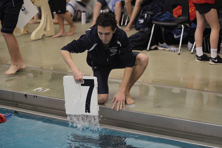Bending down, junior Jacob Tiehen pulls the lap number out of the water.