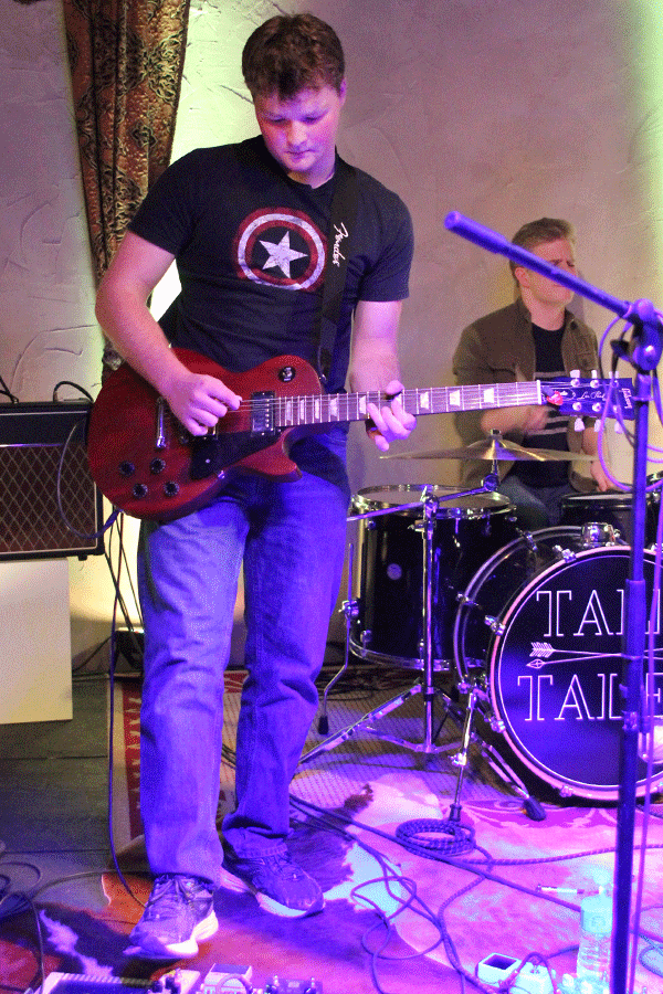 Freeman looks at his guitar to play a note.