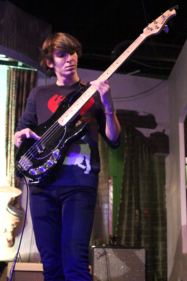 O'Halloran holds his bass guitar up as he prepares to play a note.