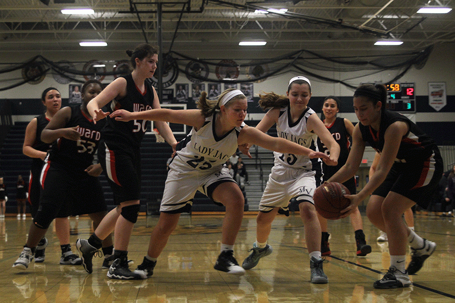 To win back possession, sophomore Payton Shurley tries to hit the ball out of a Bishop Ward players hands on Friday, Feb. 5. The Lady Jags defeated Bishop Ward 56-16.