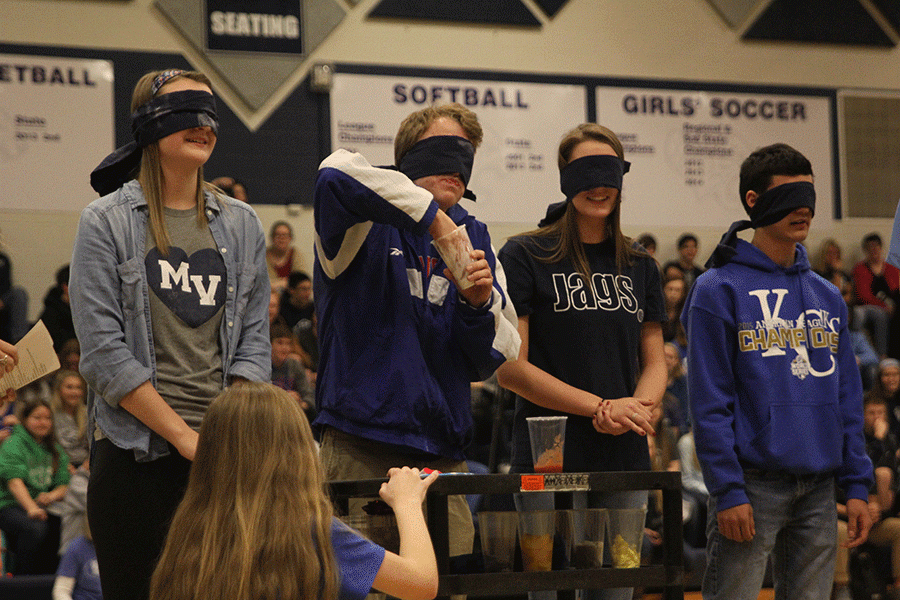 Blindfolded Homecoming king candidate Shane Calkins crams his fist into a cup after he learns it is filled with yogurt.
