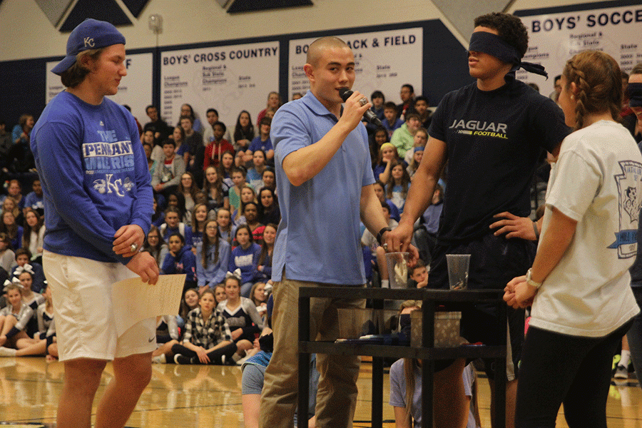 Blindfolded Homecoming King candidate Christian Jegen tries to determine what the substance in the cup is (dough) during the Winter Homecoming pep assembly.