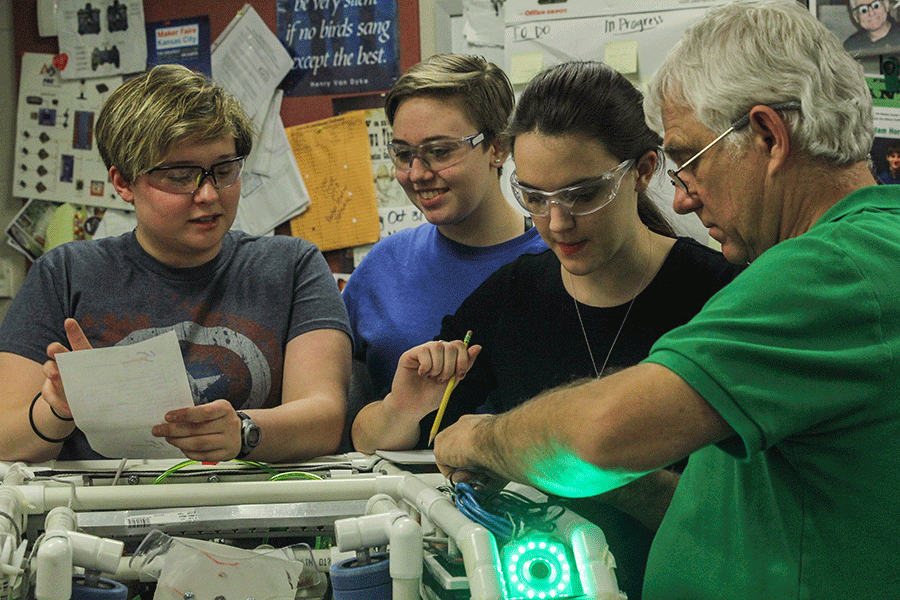 Senior Sarah Soriano goes over technical details about the teams robot with junior Taylor Barth while mentors Gary Hannah and Megan Ring work on the robot itself on Tuesday, Feb. 23.
