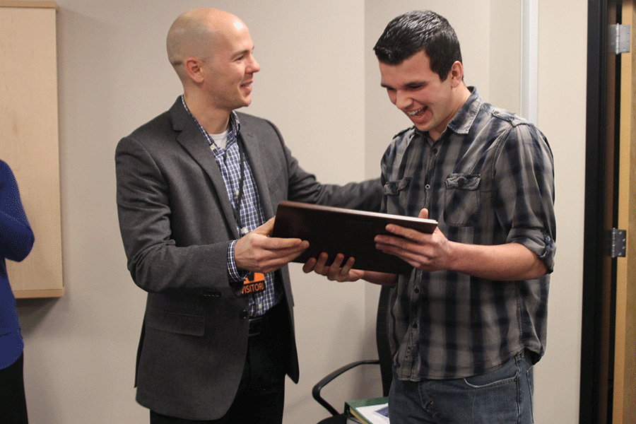 KSPA executive director Eric Thomas hands a plaque to senior student journalist of the year award recipient Justin Curto.