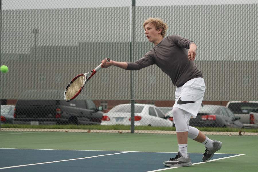 While facing Lansing in a doubles match, junior Dante Peterson reaches for a ball.