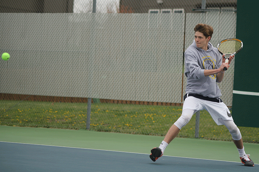 Taking a step, junior Jansen McCabe prepares to hit his opponents serve.