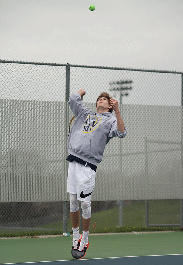 While playing in a singles match at the teams first tournament of the season, junior Jansen McCabe serves the ball.