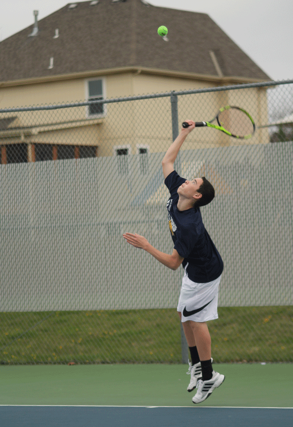 While playing against his opponent from Bishop Meige, freshman Eric Schanker serves the ball.