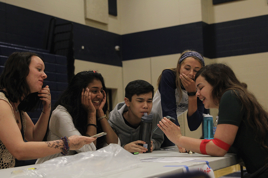Whilst eating to help her body recover, senior Madison Remijio, on Thursday, March 23, watches videos and laughs with some sophomore student council members around the snack table.
