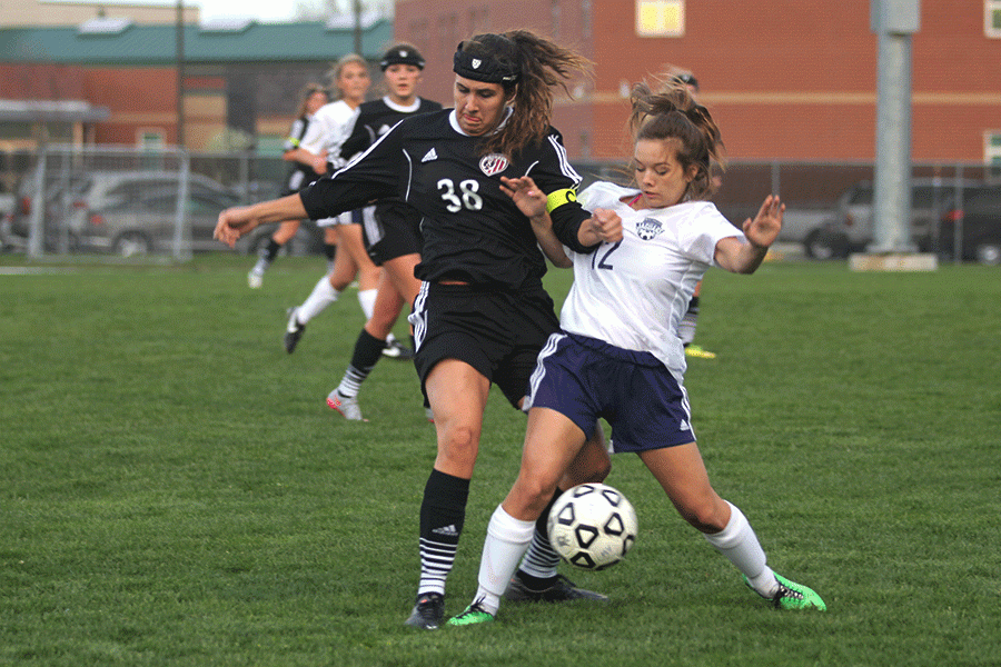 Pushing against her opponent, junior forward Paige Lewis battles for the ball.