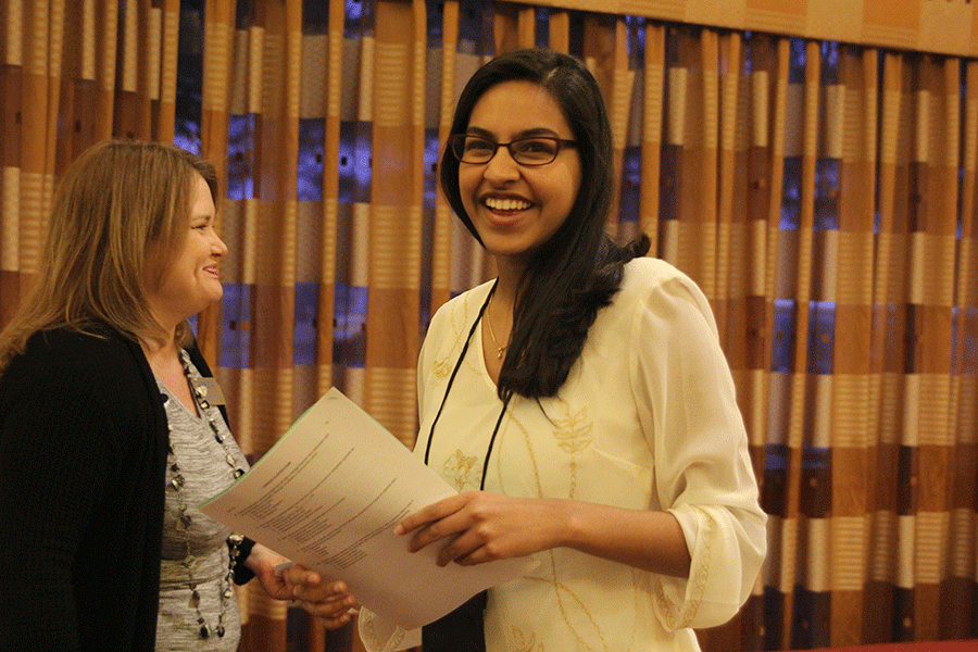 Smiling outside the testing room, senior Nadia Suhail receives her testing packet.