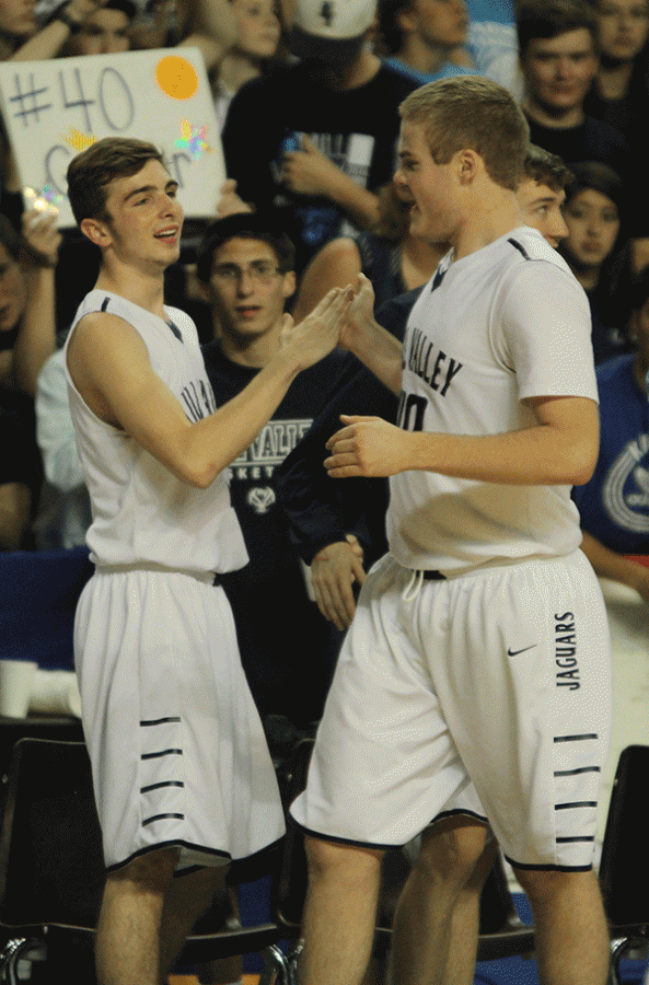 As he comes off the court, senior Tyler Grauer high fives senior Ethan Lane.