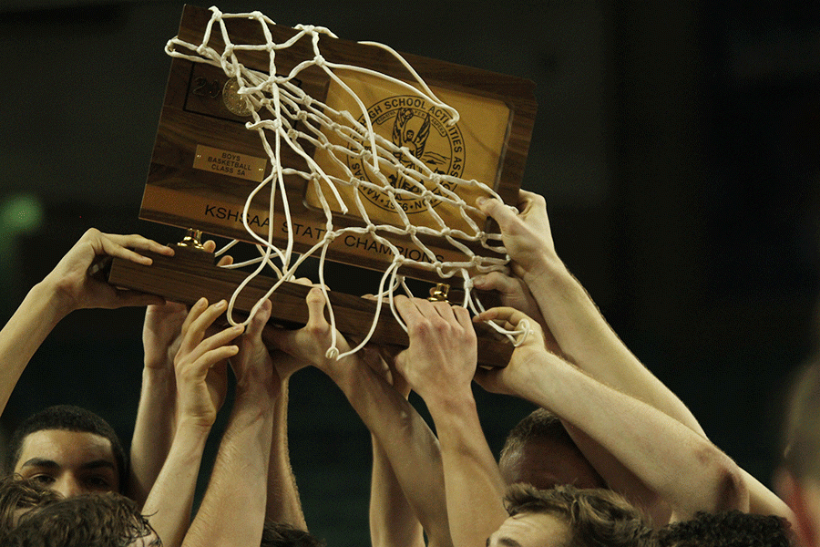 The team holds up the state champions trophy at the end of the game.