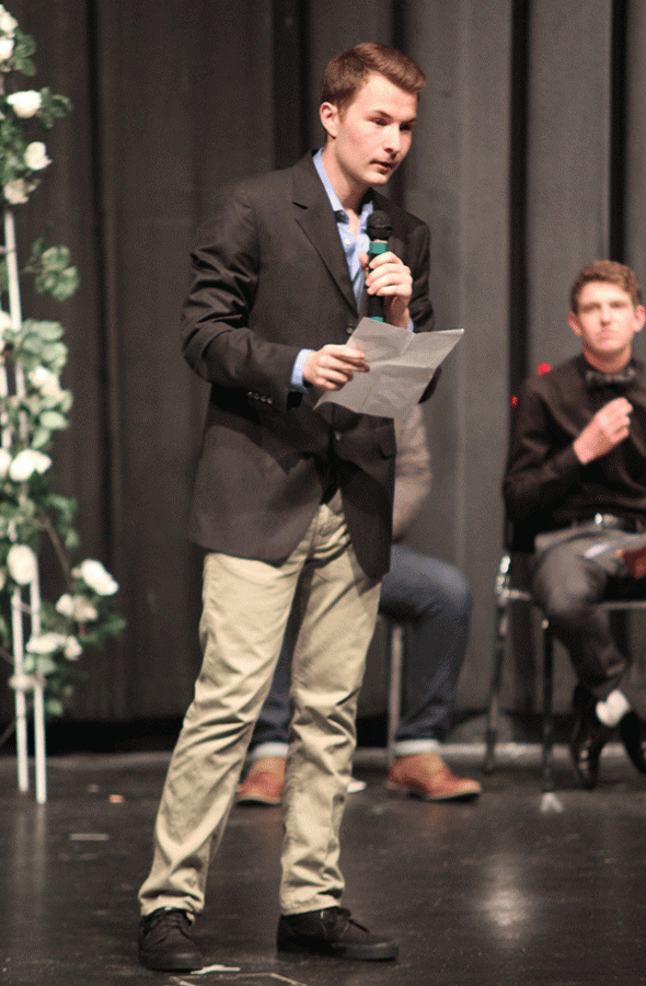 Junior Austin Garner holds his poetry in his hand with a microphone as he reads.