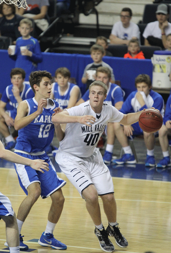 Boxing out his opponent, senior Tyler Graurer dribbles toward the basket.