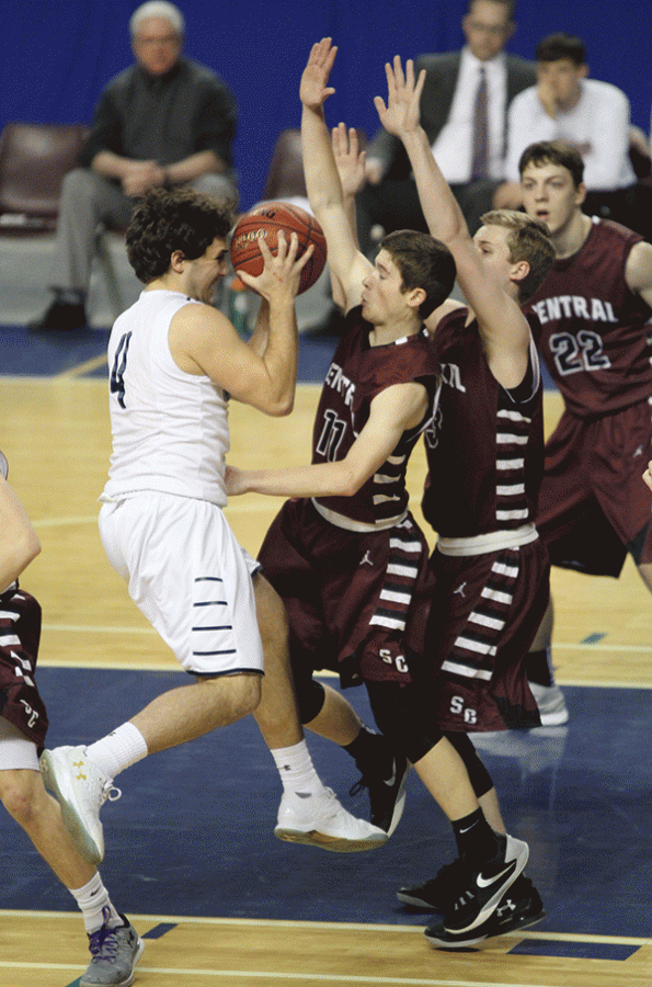 Dodging his opponents, senior Logan Koch jumps to shoot a basket.