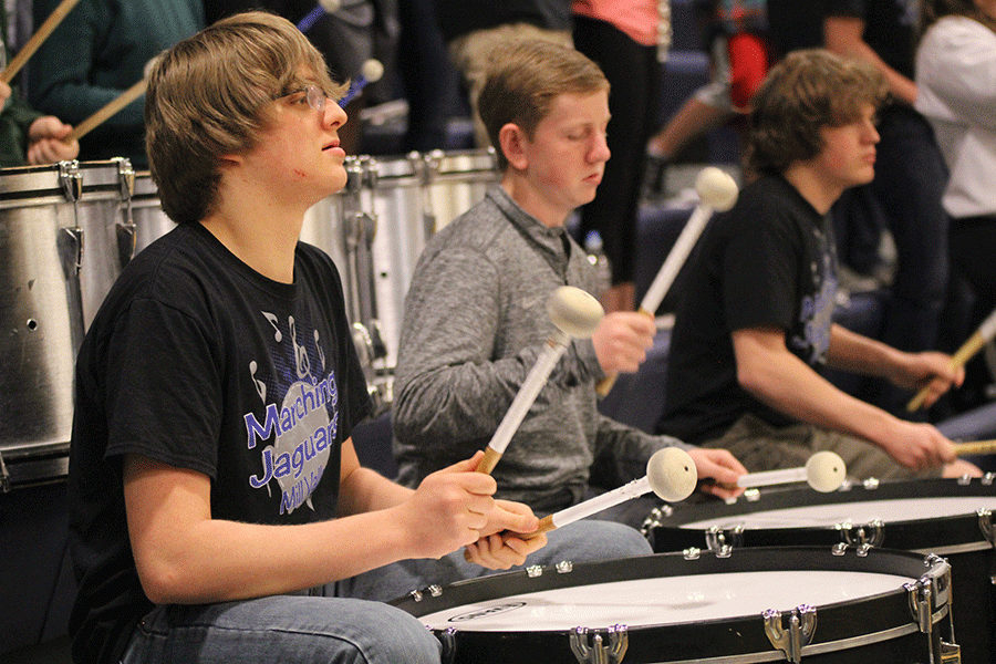 Junior Derek Simms plays the bass drum during halftime of the boys basketball game.