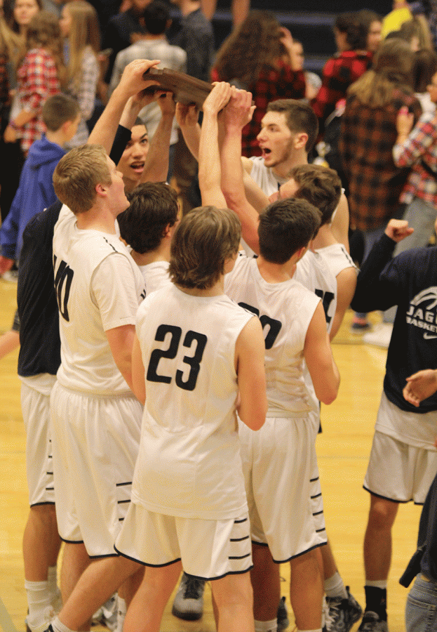 After winning sub-state, members of the boys basketball team hold up their newly received plaque.