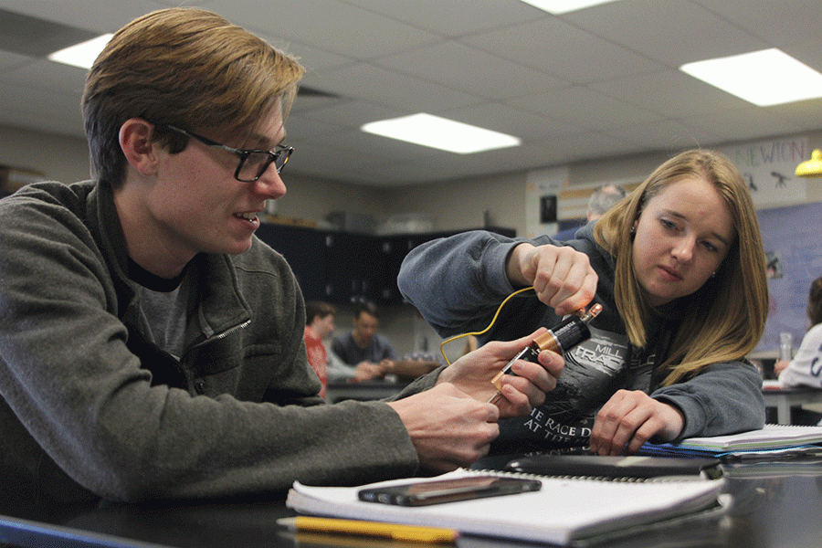 Senior Brian Fitzsimmons holds two batteries together as junior Lauren Atchley touches a lightbulb to one end during a Physics lab on Friday, Feb. 26. 