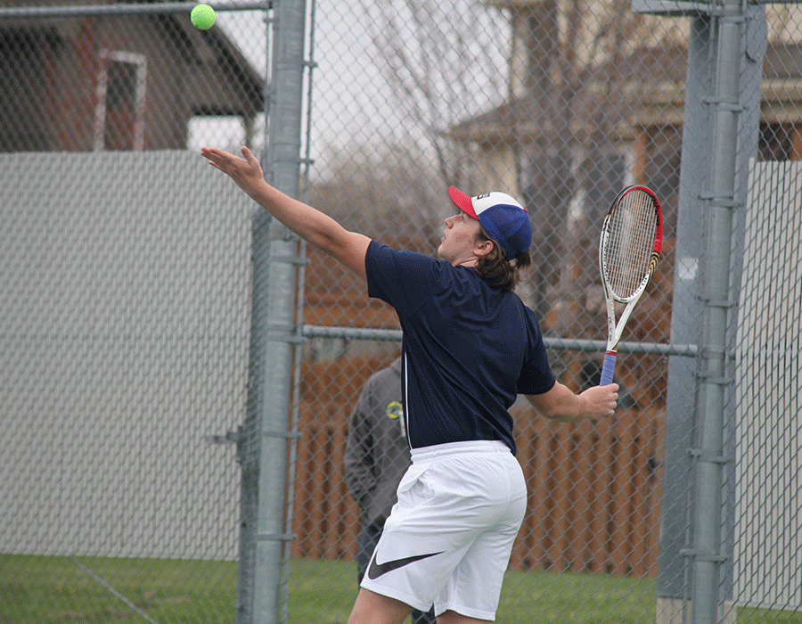 Tossing up the ball, senior Tyler Shurley begins his serve during a doubles match. 