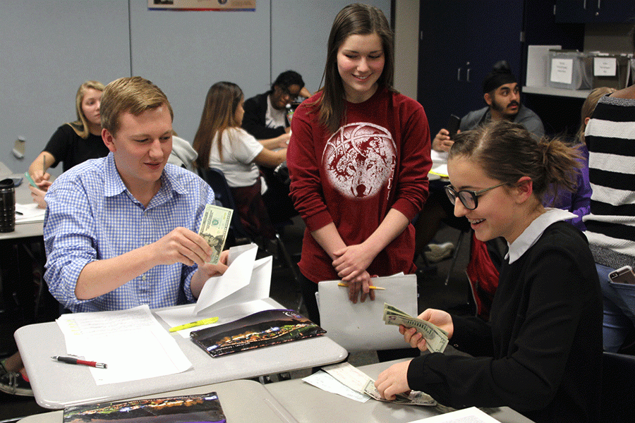 Handing in money for her group’s donations, freshman Lauren Rothgeb talks to junior Brady Rolig during a meeting on Wednesday, Feb. 24. “I’m just really excited to spend time with friends for a good cause,” Rothgeb said. “[We’ll] just have a lot of fun.”