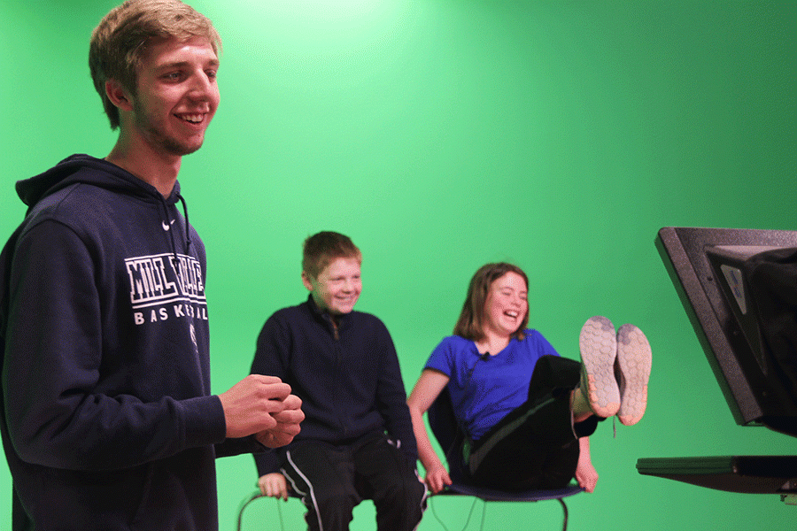Prairie Ridge Elementary fifth graders giggle as junior Eli Soell shows them some tricks with the green screen on Friday, March 25.