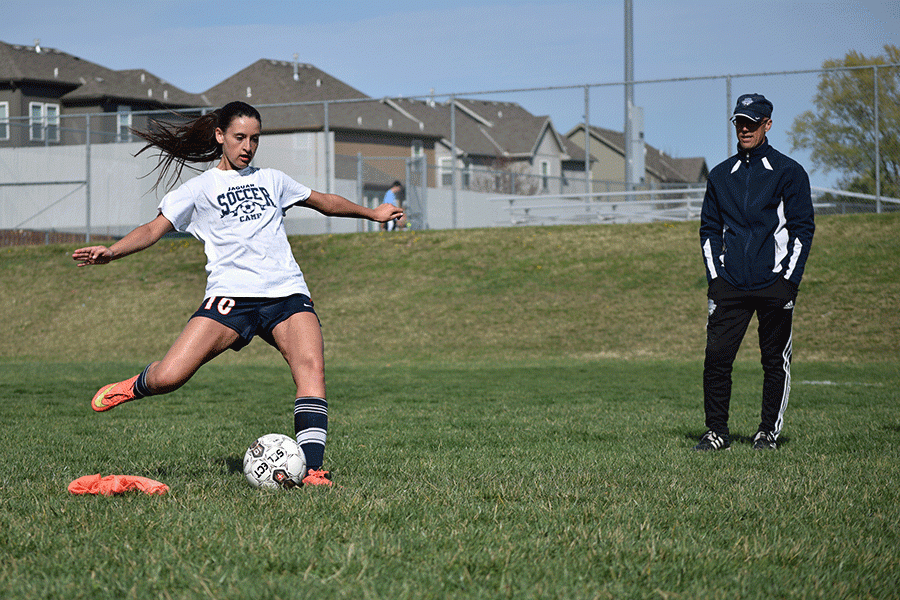 While recieving coaching from head girls soccer coach Arlan Vomhof, junior defender Lauren Moores takes a shot at the goal during practice on Friday, March 26. 