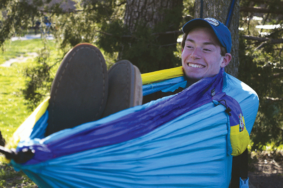 Smiling, senior Brian Fitzsimmons hammocks at Garrett Park alongside his friends on Saturday, April 2. 