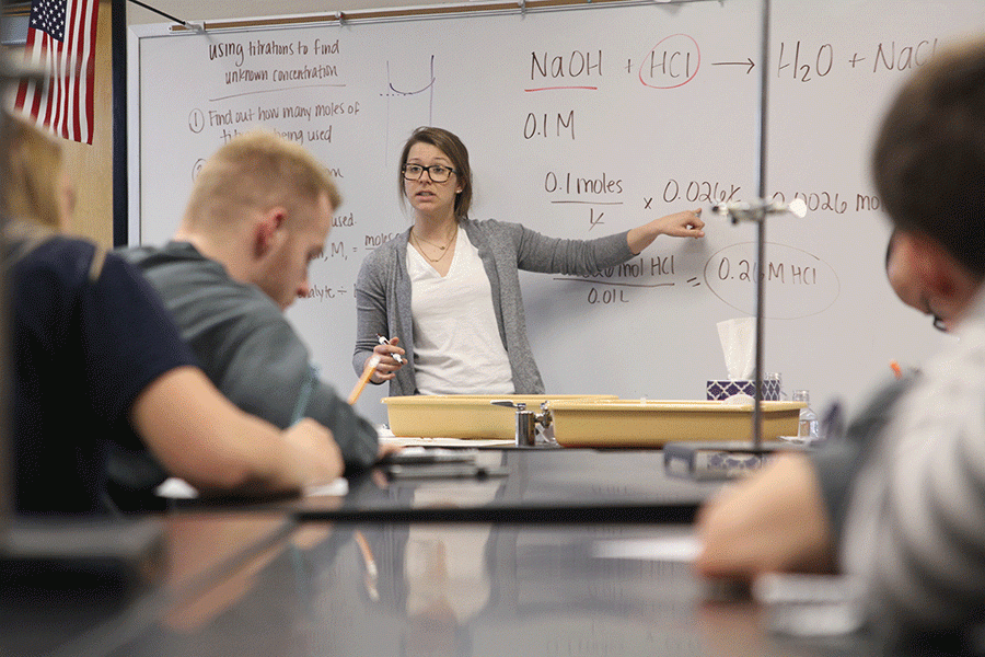 After the conclusion of the titration lab on Thursday, March 21, science teacher Jessica Haney goes over chemical amounts and equations for sophomore Myles Mustapich’s chemistry class. The lab will kick off the start of the titration unit where students learn about neutralization. “When she teaches she is really fun and it helps me learn a lot,” Mustapich said. 