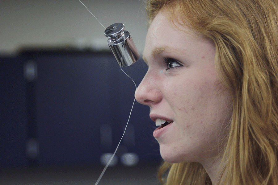 As the pendulum swings toward her face, junior Diana Auckley stands in place to get accurate results of how close the pendulum can get to her face without hitting her for a physics lab on Wednesday, April 27. “It was slightly terrifying,” Auckley said. “I backed away from it a couple times but eventually I was brave enough to stand still.”